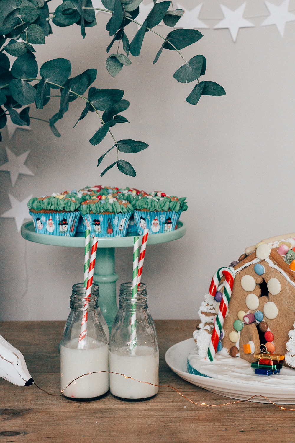 Festive desert table with gingerbread house, Christmas cupcakes and milk bottles