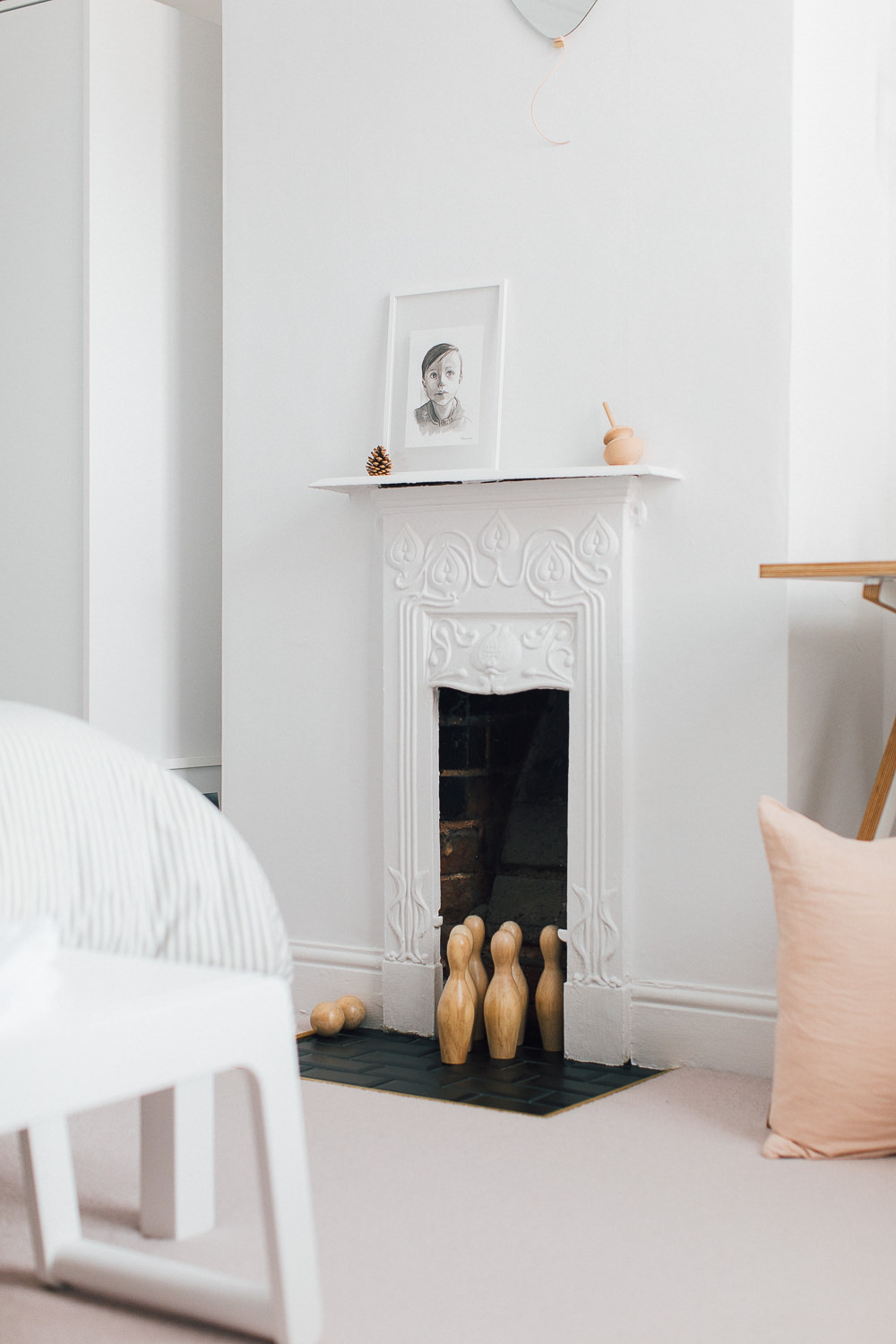 White Victorian cast iron fireplace | Wooden skittles | Illustrative prints | A modern neutral millennial pink bedroom for children with handmade furniture, personalised artwork and statement lighting